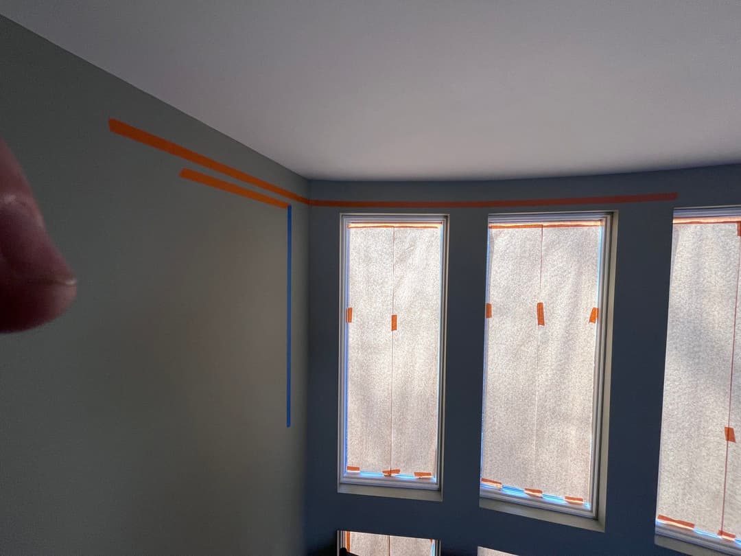 Room with windows and painter's tape outlining a fresh paint job.