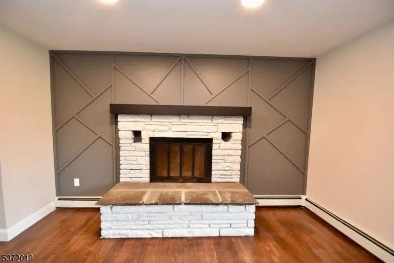Modern living room featuring a stone fireplace and gray accent wall with geometric design.