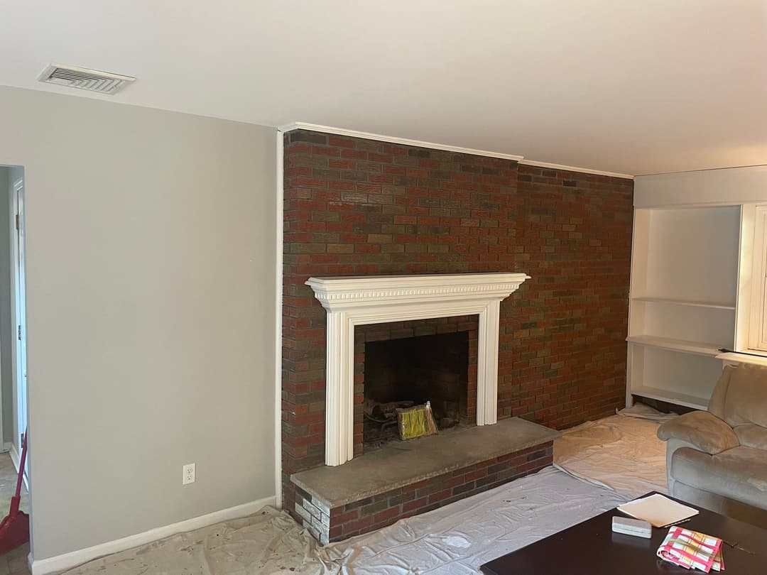 Living room with a brick fireplace and neutral walls, featuring a cozy, inviting atmosphere.