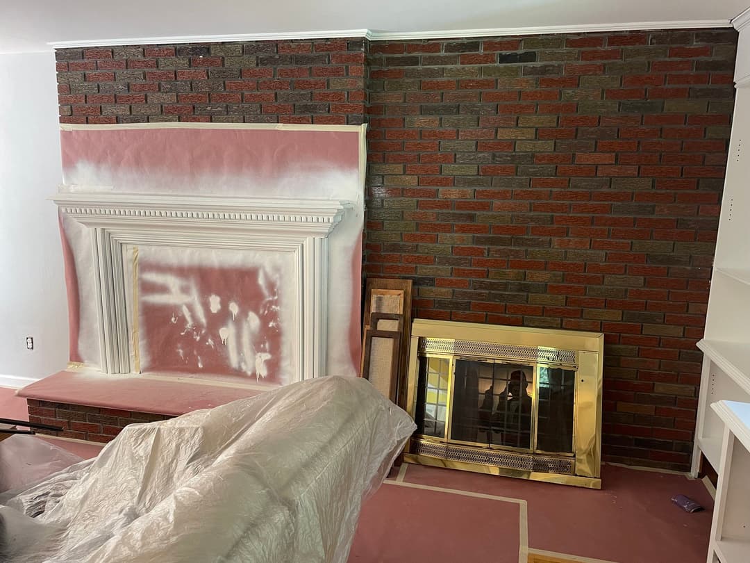 Living room with unfinished brick wall and fireplace renovation in progress.