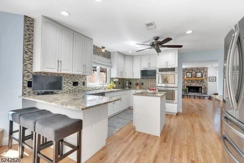 Modern kitchen with granite countertops, white cabinets, and stainless steel appliances.