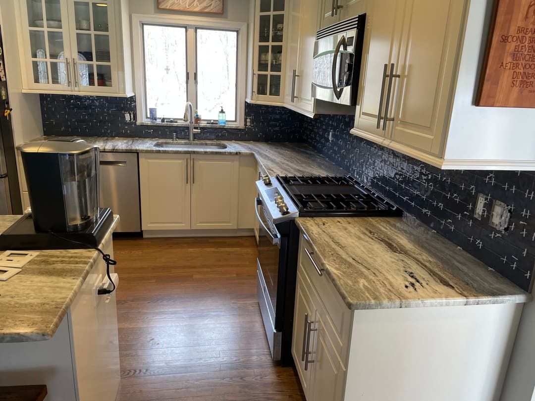 Modern kitchen with white cabinets, stainless steel appliances, and granite countertops.