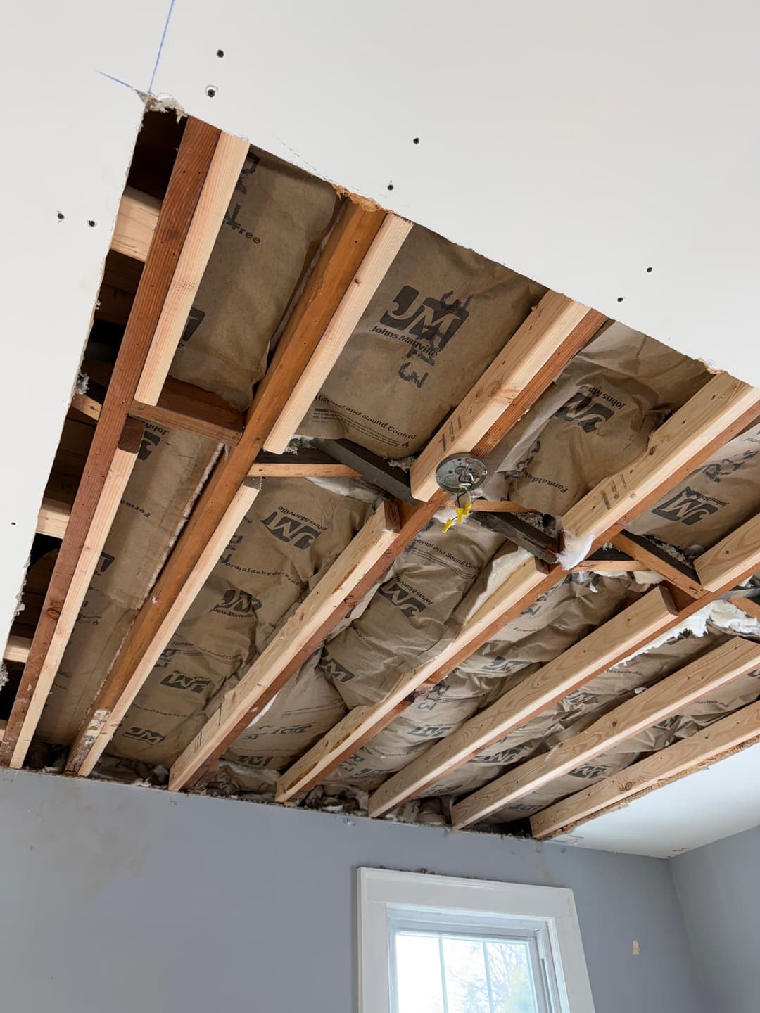 exposed ceiling framing with insulation and electrical wiring in a renovated room