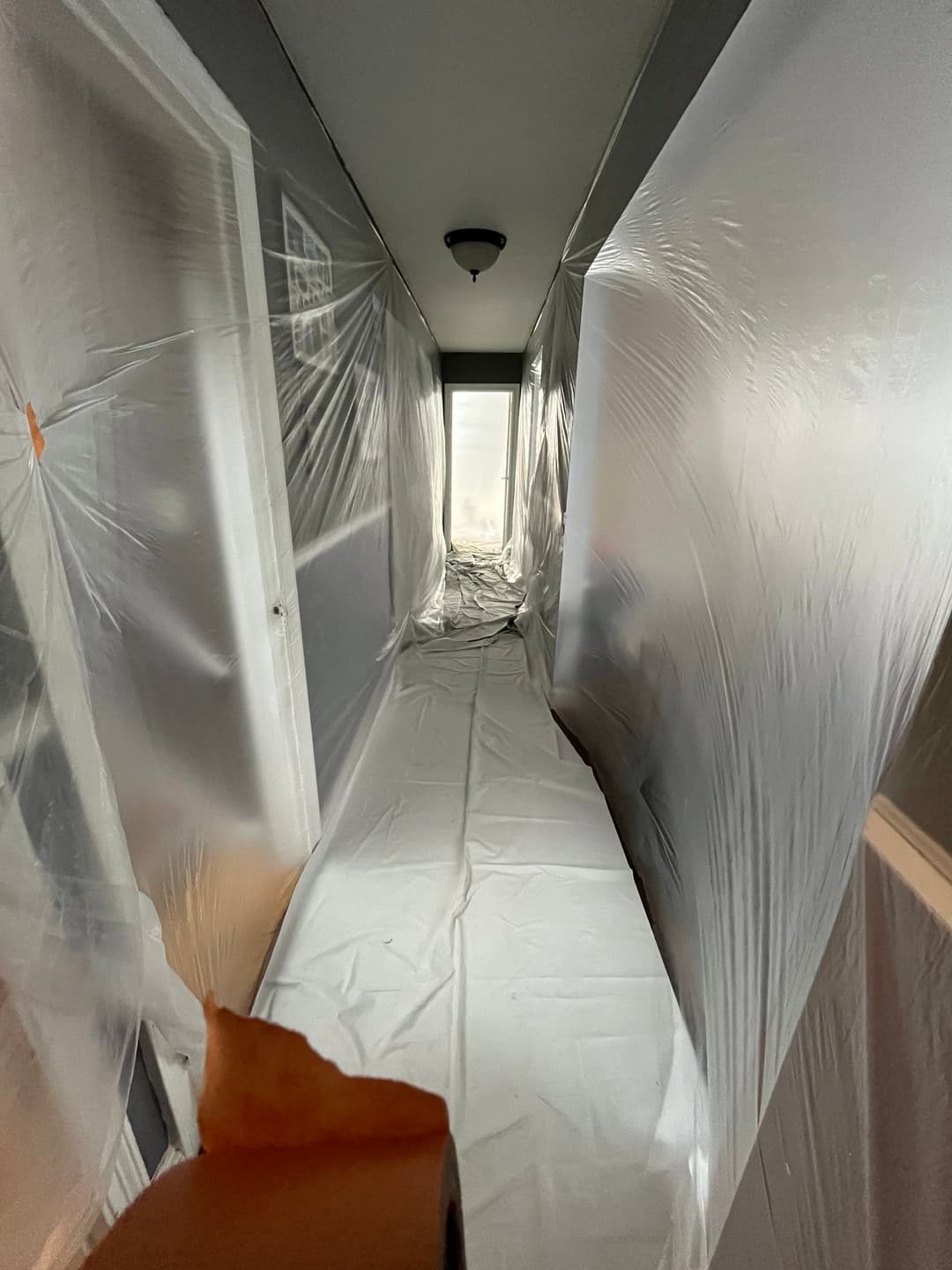 Plastic sheeting covers a hallway, creating a barrier for painting or renovation work.
